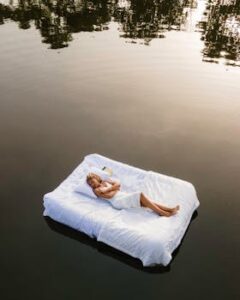 A woman enjoys peaceful relaxation on a floating mattress on a tranquil lake.